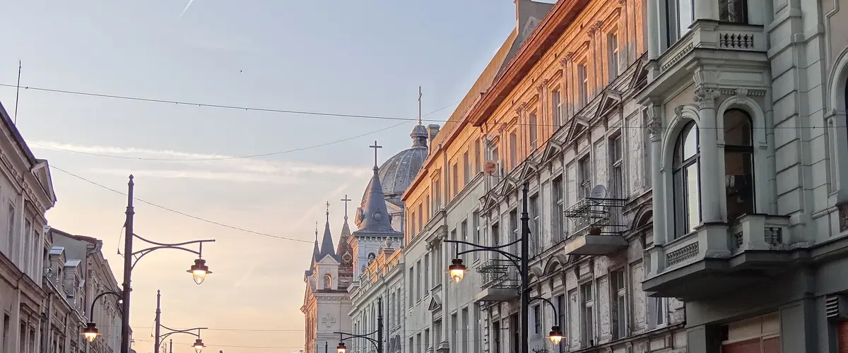 Ulica Piotrkowska w Łodzi o zmierzchu, kamienice i latarnie